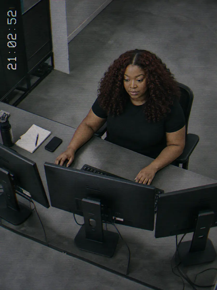 Surveillance still of Shené working at a triple monitor setup