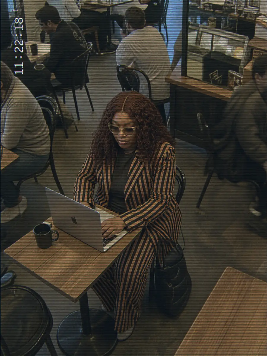 Surveillance still of Shené working on a laptop in a café